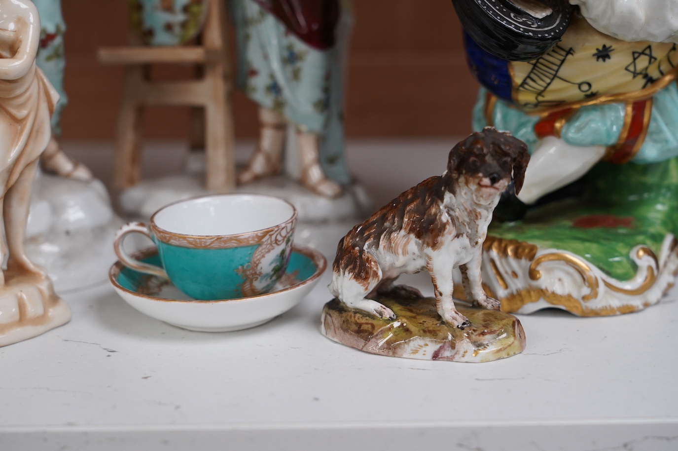 A 19th century French Mansion House Dwarf, a pair of Volkstedt figures, a Meissen dog, cup and saucer and a German porcelain female sculpture, tallest 21cm. Condition - fair to good, a few minor chips